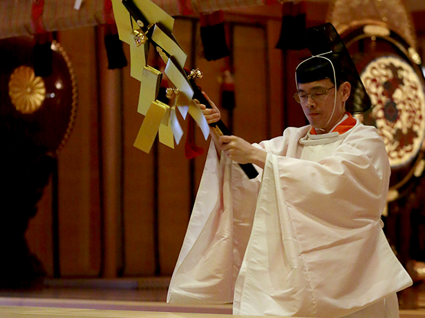 A priest passes with bells in front of participants.